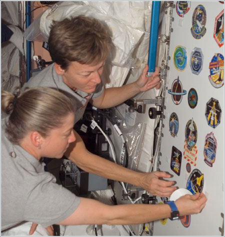 Pam Melroy y Peggy Whitson colocan el escudo de la misión STS-120 en el módulo Unity / NASA