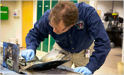 Técnico de la NTSB inspeccionando los restos de la batería